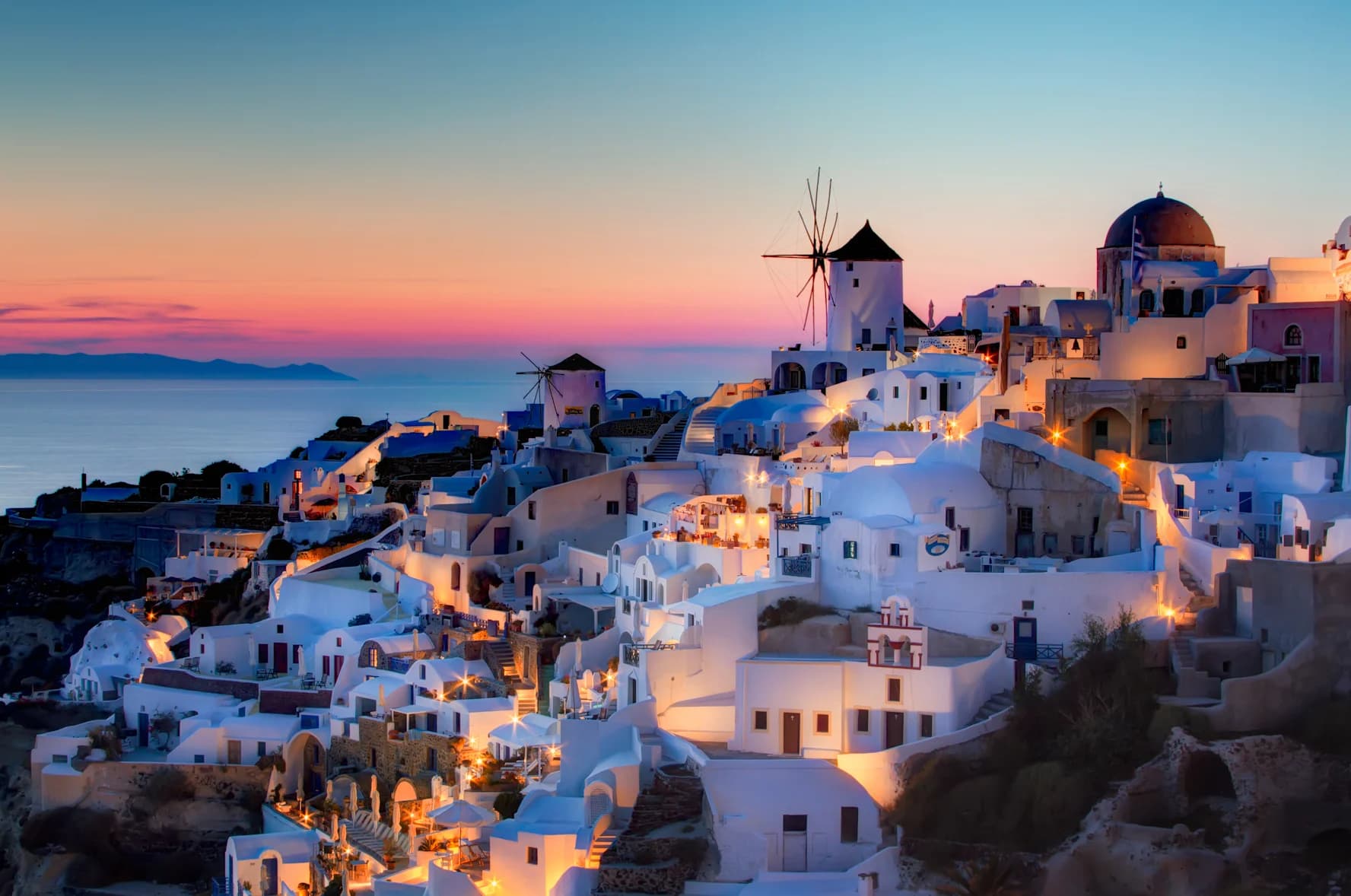 Blue-domed churches overlooking the Santorini caldera at sunset