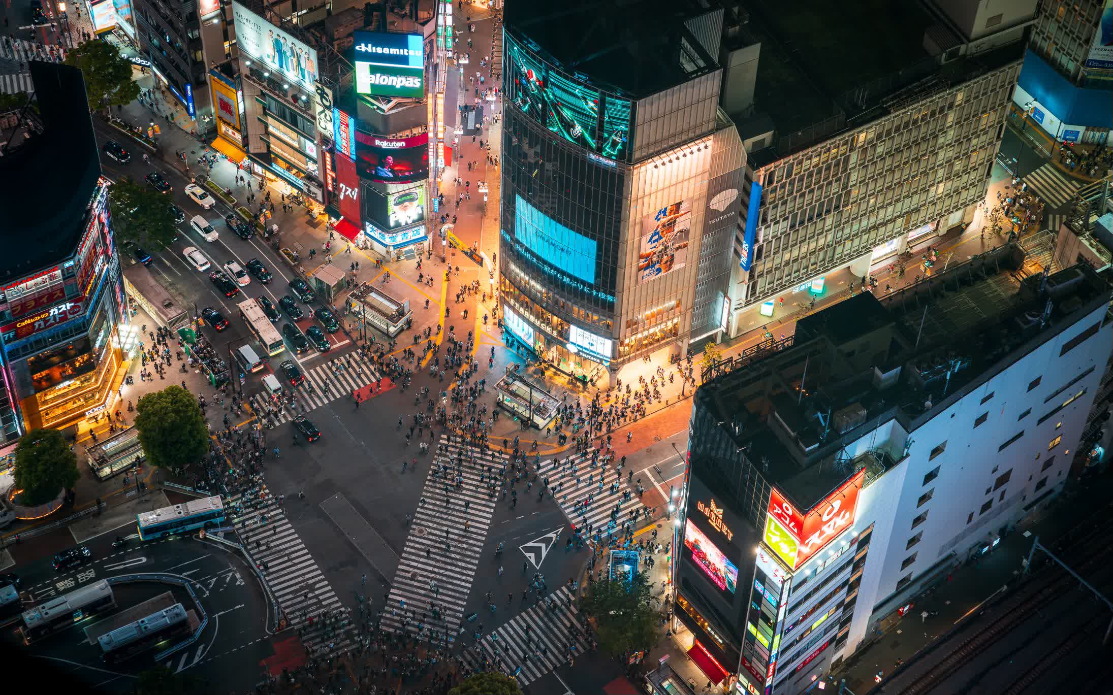Crowds crossing the illuminated Shibuya Crossing at night in Tokyo